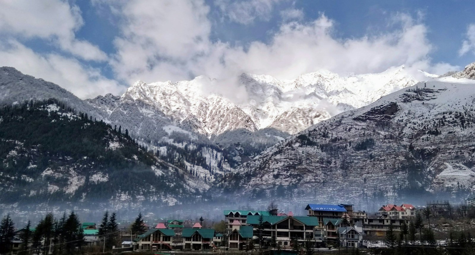 Manali buildings below snow-covered mountains